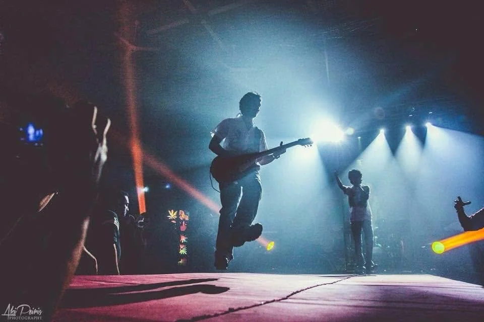Guitarist silhouetted in dramatic stage lights